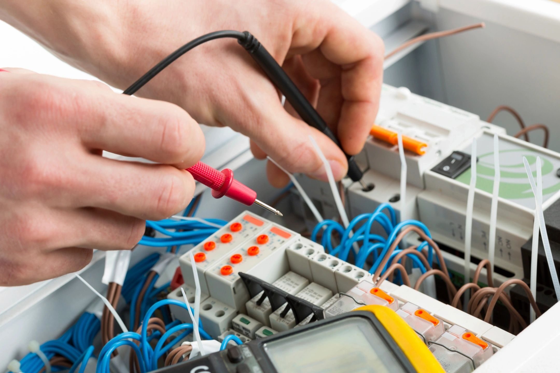 A person working on electrical equipment with wires and cables.