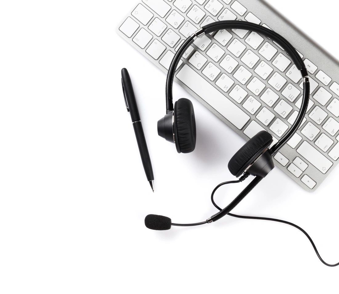 A keyboard, headphones and pen on top of the table.